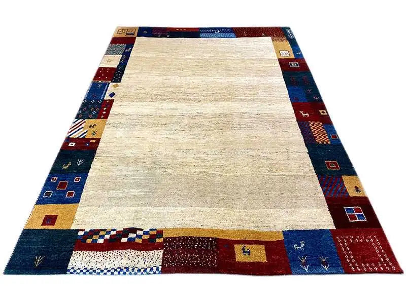 Gabbeh rug with beige pile and a dark blue border, high-contrast patterns and appliqués