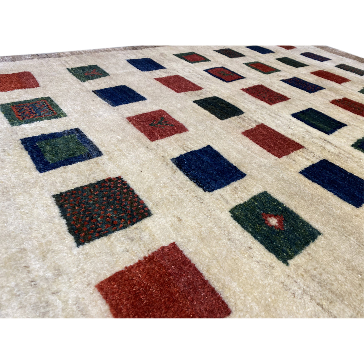 Gabbeh rug close-up: colorful squares on a beige background, with a dark border
