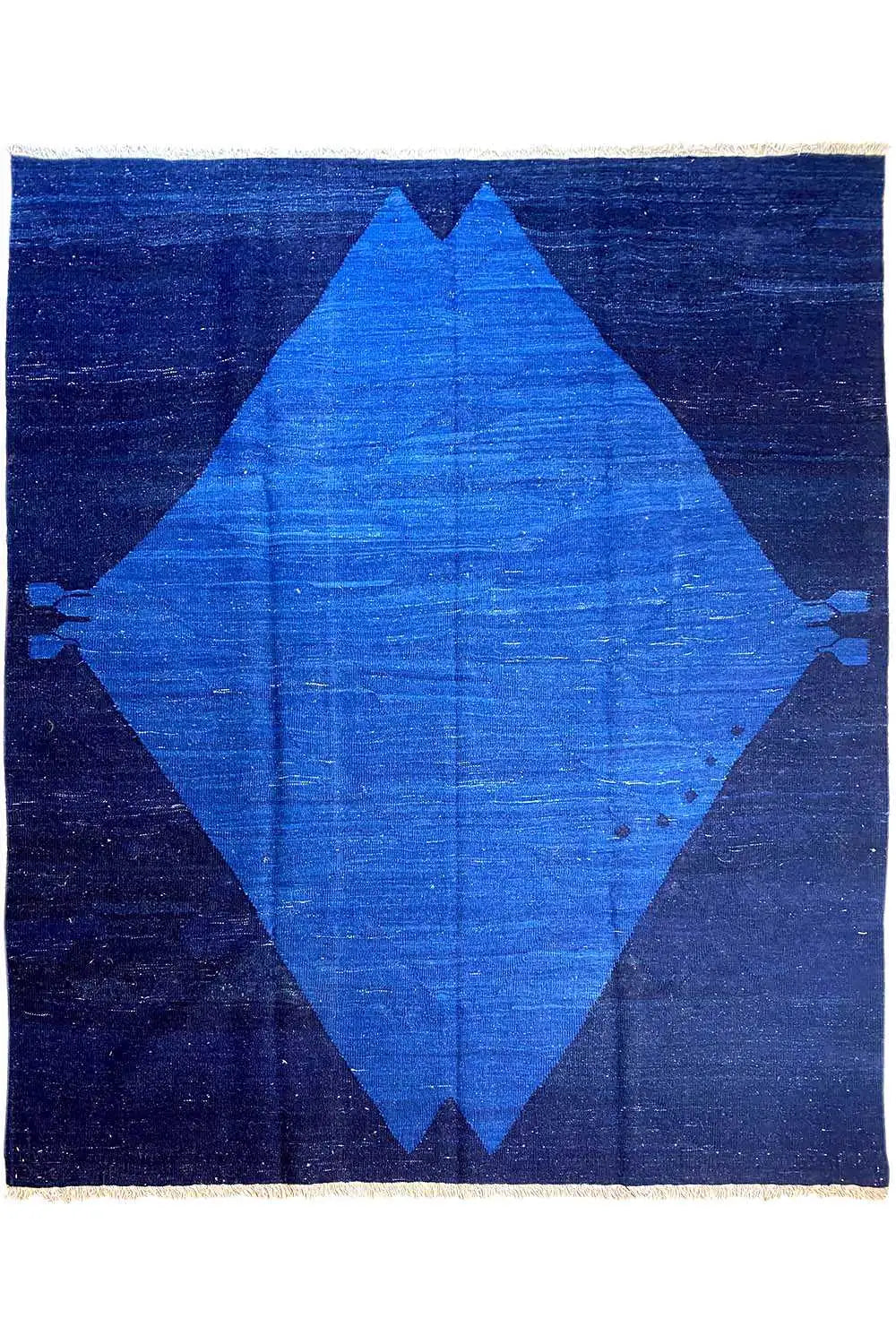 Blue rug with a dark border and a large blue diamond pattern