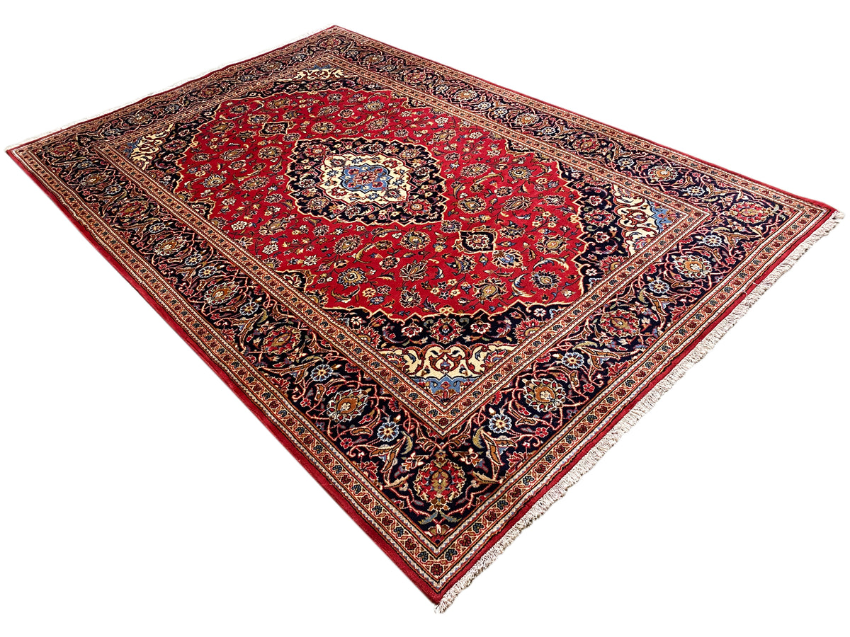Orientteppich in Rot mit feinen Ornamentbordüren und zentraler Rosette, diagonale Ansicht