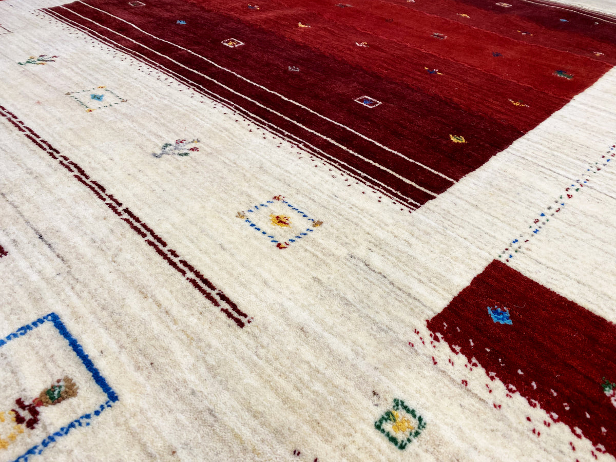 Loom Luri Teppich Detailansicht: cremefarbene Fläche mit roten Streifen und Mustern