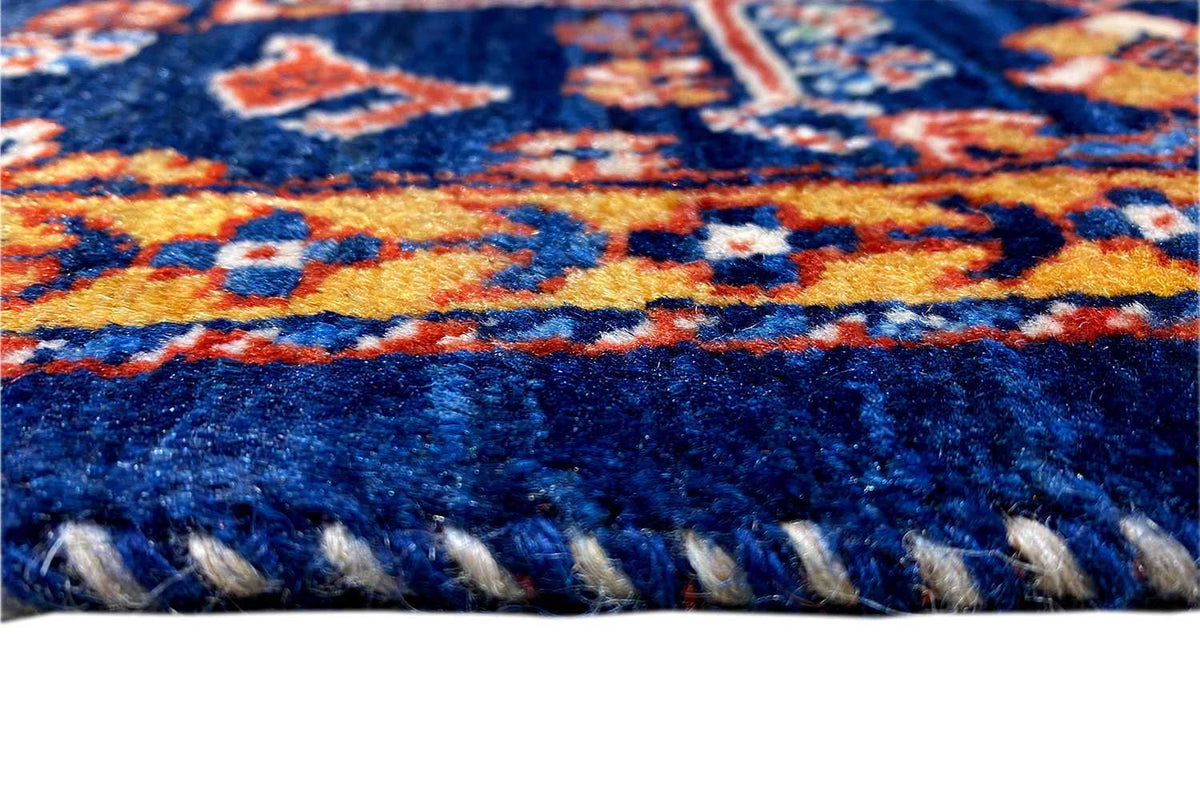 Rug fringe along the blue edge, textured wool with colorful ornamental bands