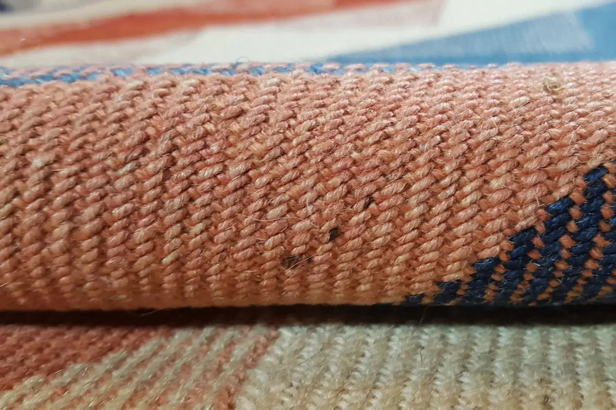 Close-up of the carpet surface: beige pile with a blue-red zigzag stripe