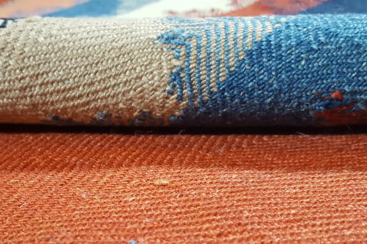 Close-up of the carpet surface: orange woven texture with blue accents