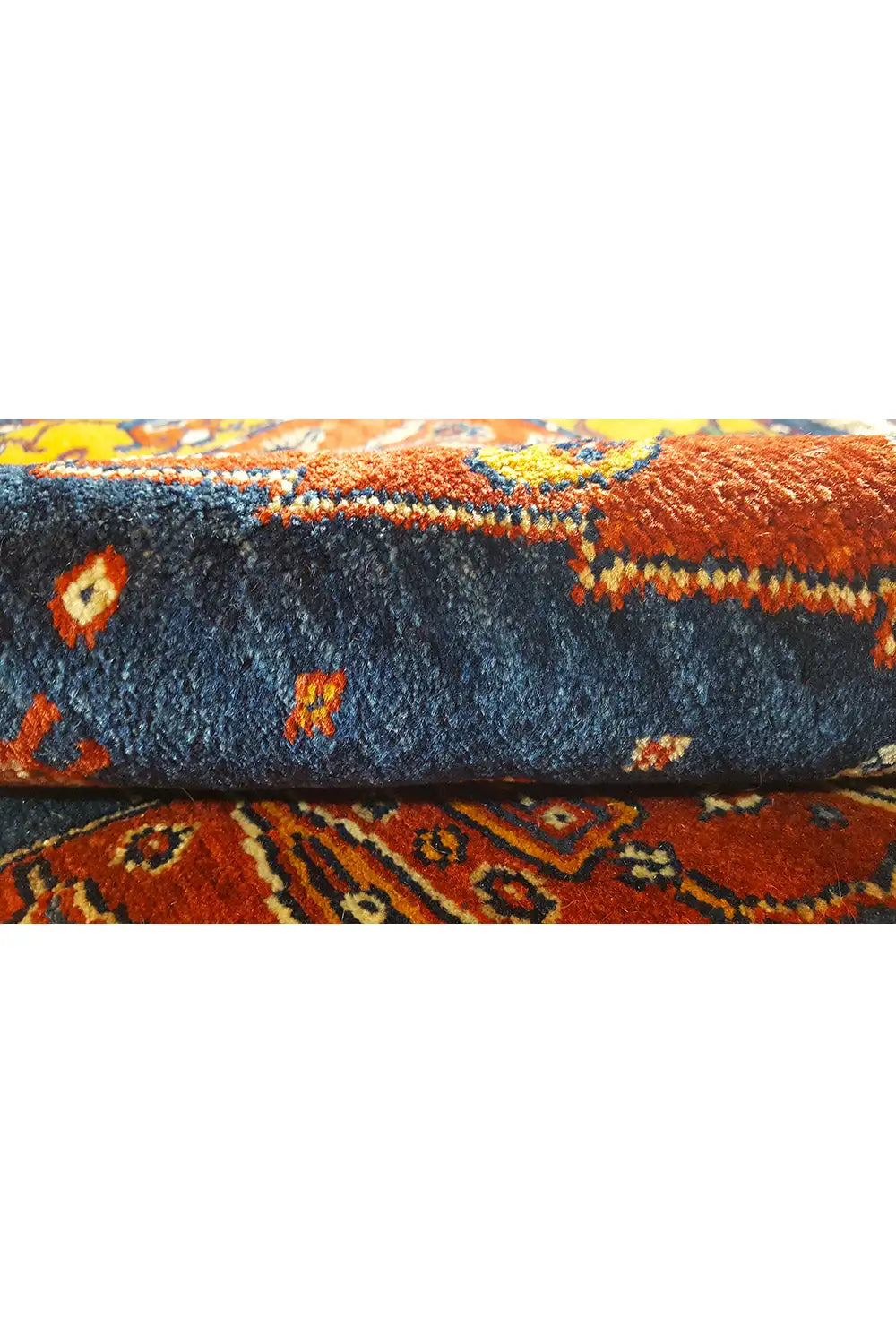 Close-up of a Gabbeh rug: blue pile with orange accents and fringe.