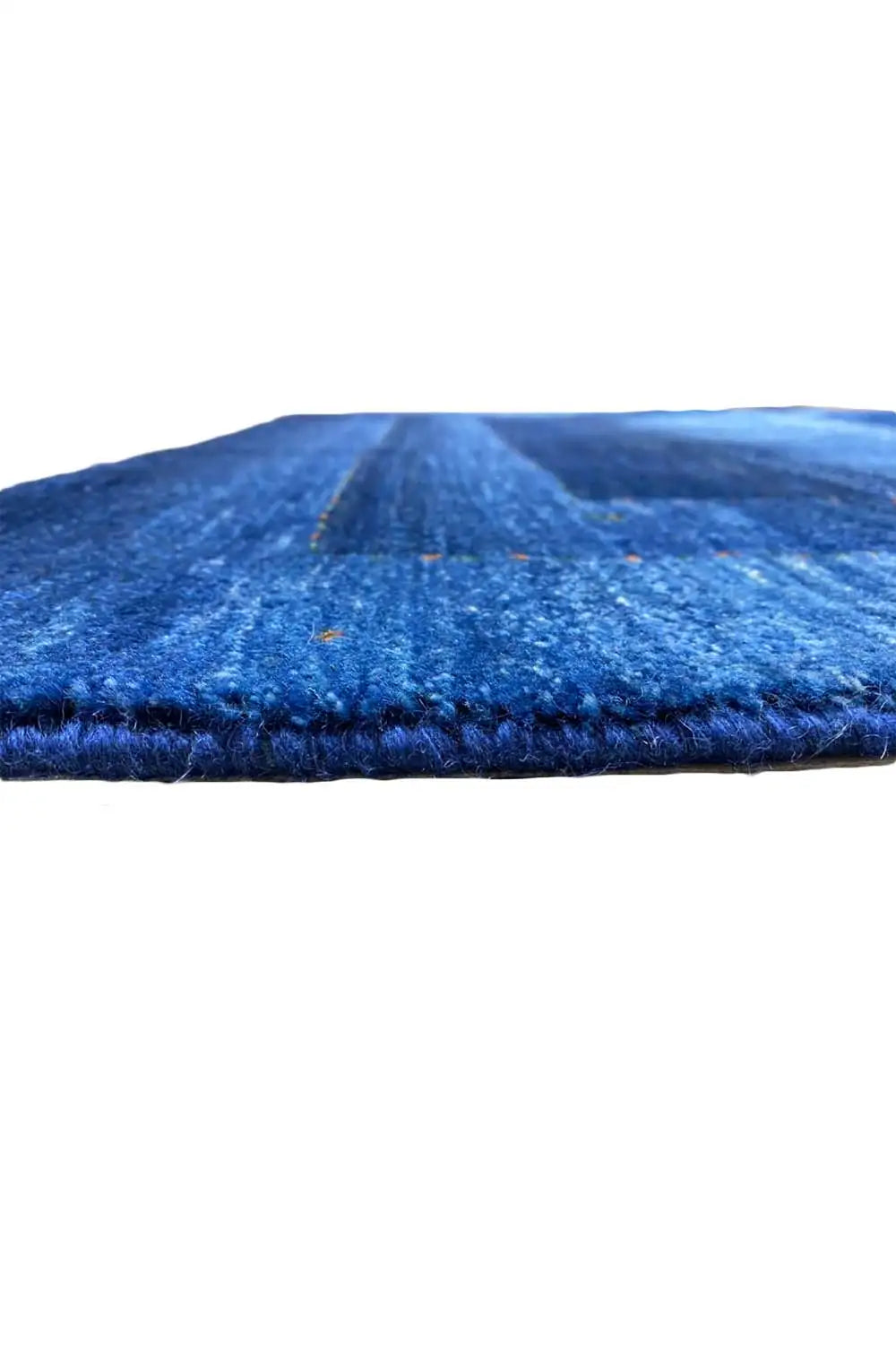 Blue Gabbeh rug with visible pile height and folded edge