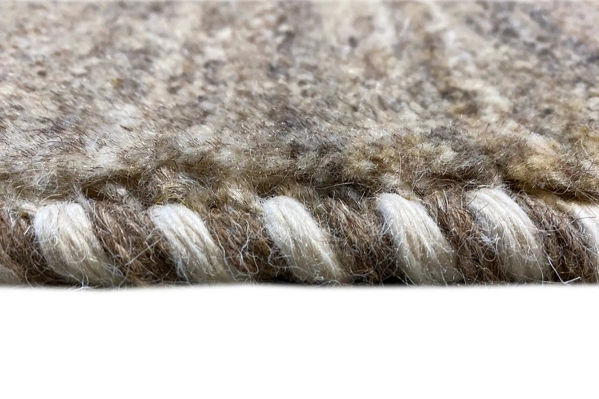 Gabbeh rug close-up: fringed edge and dense beige pile