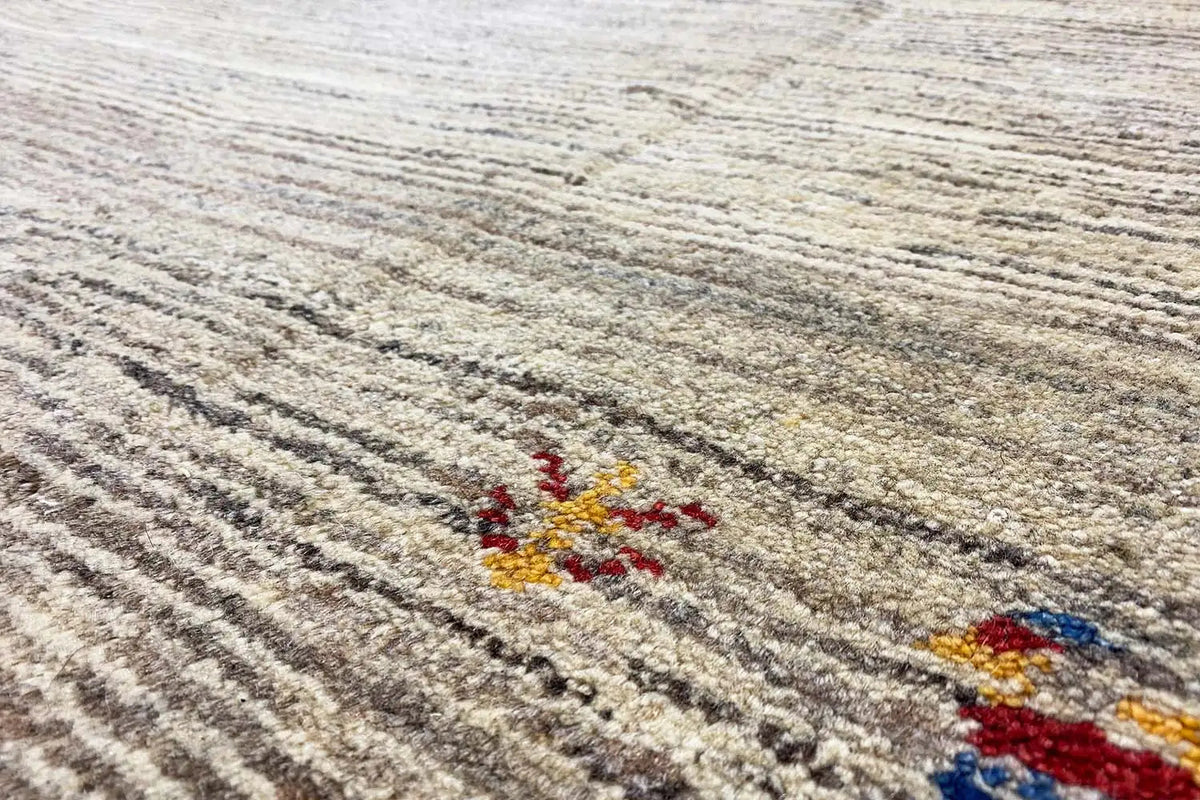 Gabbeh rug: beige low-pile weave with dark lines and colorful embroidered motifs