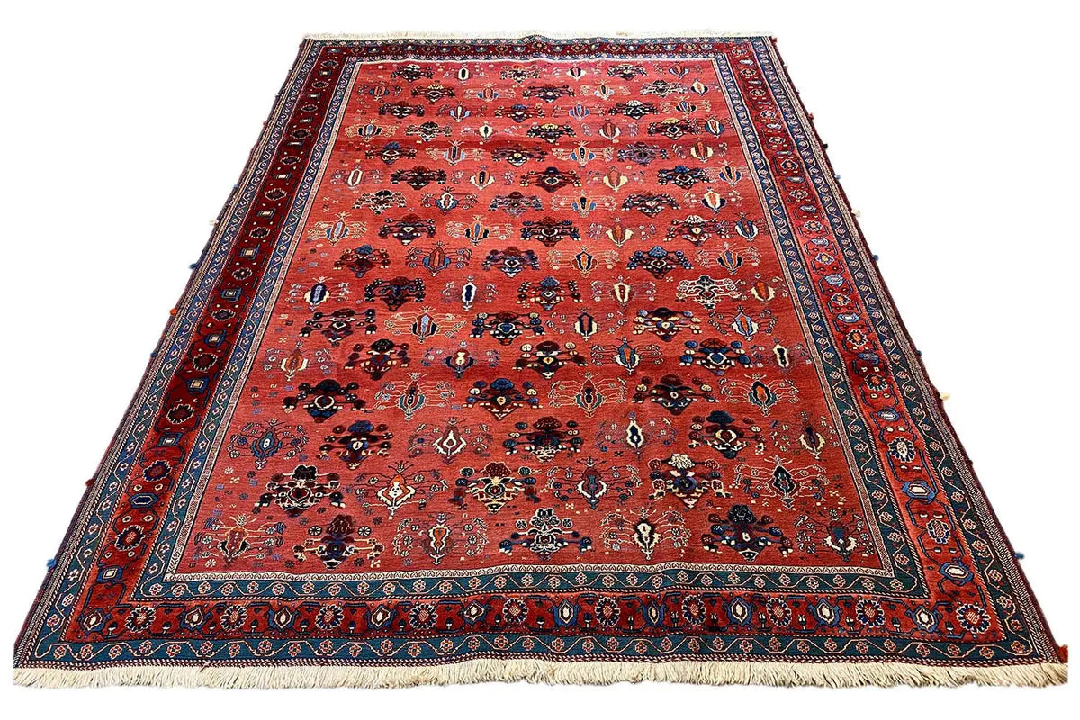 Large rectangular rug with a reddish-brown background, blue border, and fringes