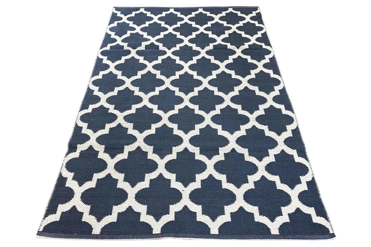 Kilim rug with a dark blue background and white geometric pattern, lying flat