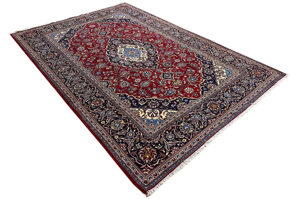 Keshan rug laid out, red center with multicolored details and a dark border