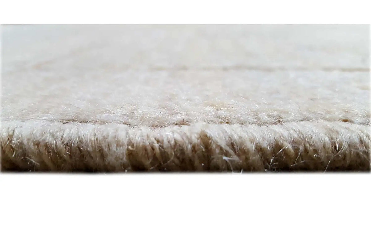 Close-up of a Gabbeh rug: beige pile with short fringe along the edge