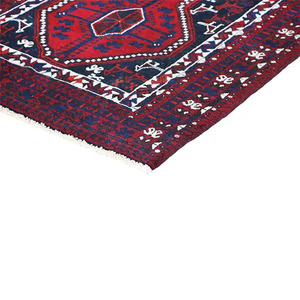 Corner view of an Oriental rug with a dense border and geometric motifs in red and blue