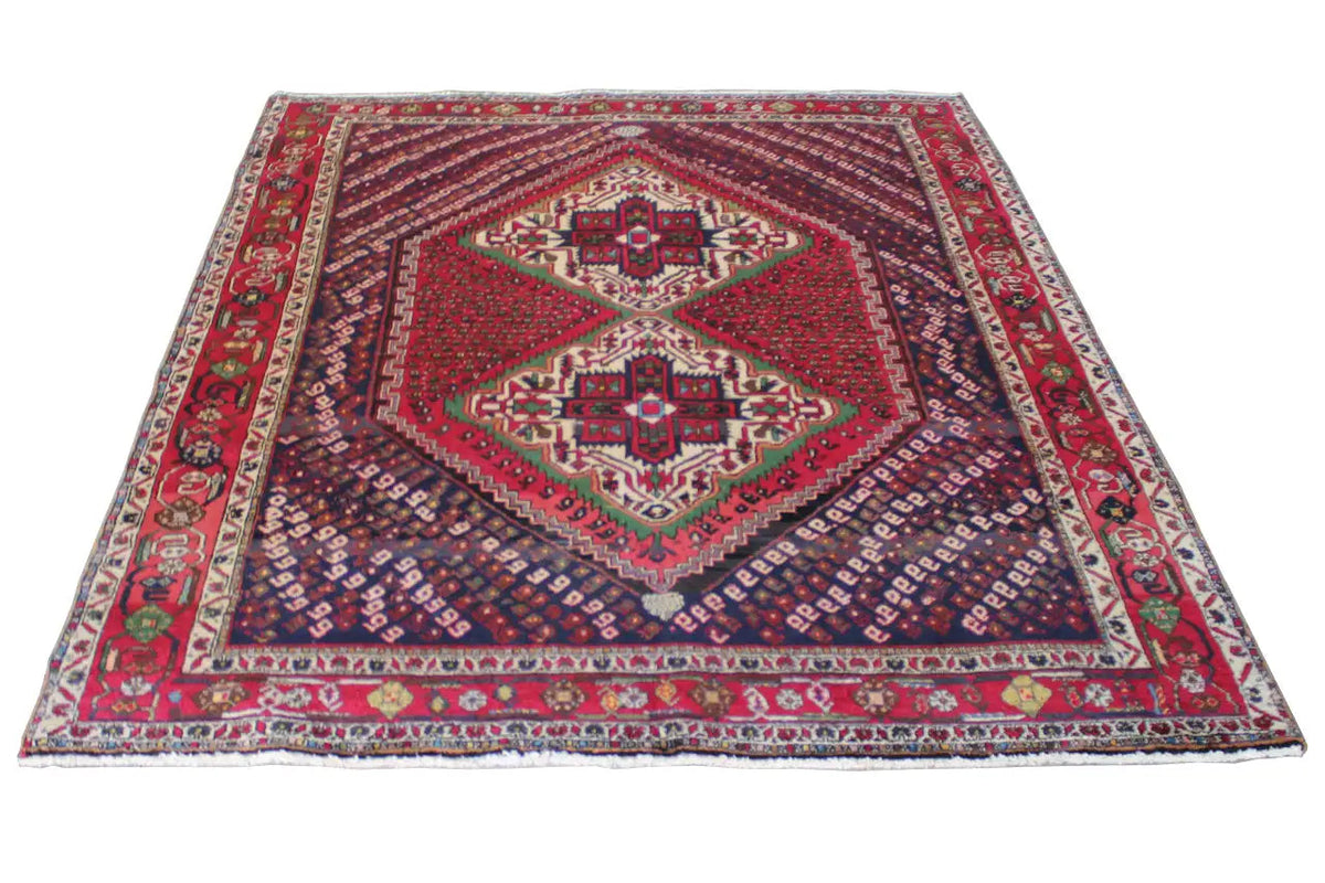 Oriental rug lying flat with a red star medallion, blue-red field, and decorative border.