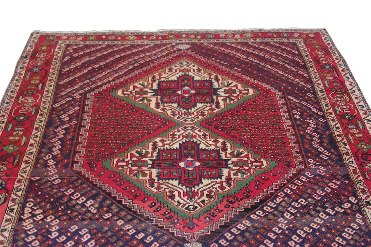 Oriental rug with a red field, central diamond medallions, and a decorative border.