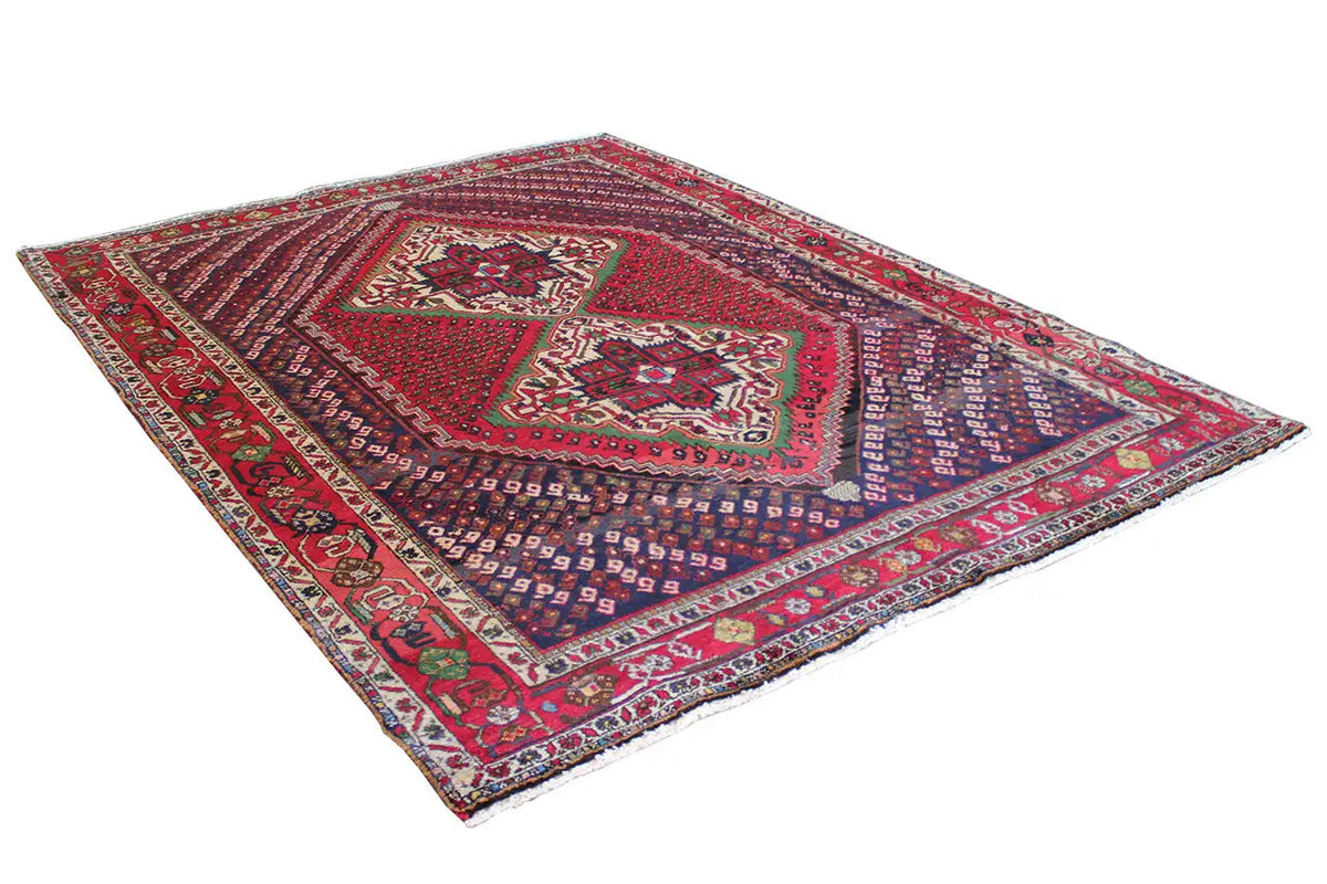 Oriental rug spread diagonally: red field, blue geometric pattern and borders.