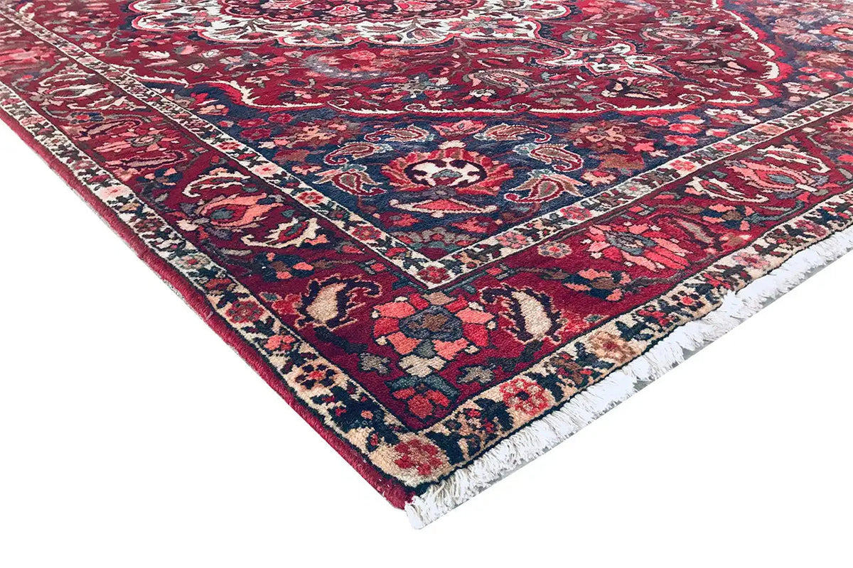 Carpet corner with hem: red pattern, dark blue area, and multicolored decorative border.