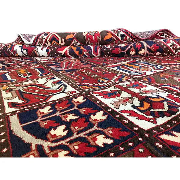 Close-up of a Bakhtiari rug: burgundy, cream, and dark blue ornamental panels, frayed edge