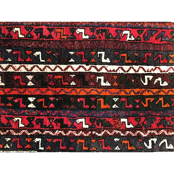 Close-up: border and patterned stripe on a rug in dark red, black, blue, and cream