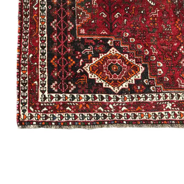 Close-up: red carpet with border pattern, multicolored ornaments, fringed edge