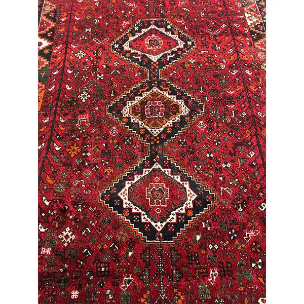 Red Oriental rug with central medallions and a dense black-and-cream pattern