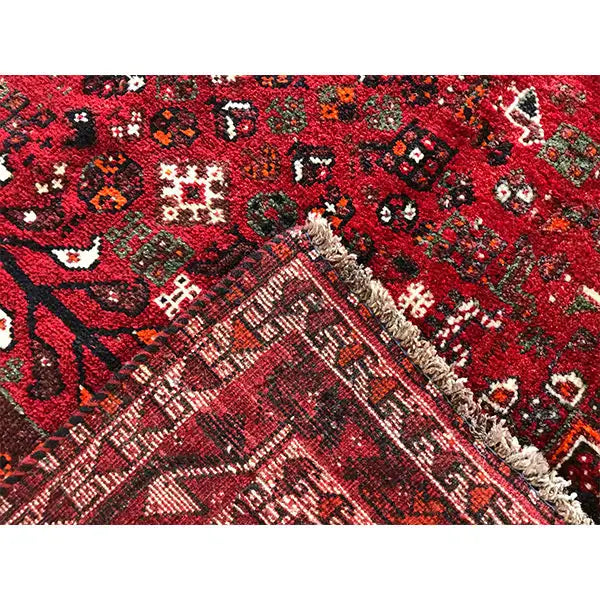 Close-up: red carpet fabric with a high-contrast pattern and fringes along the edge