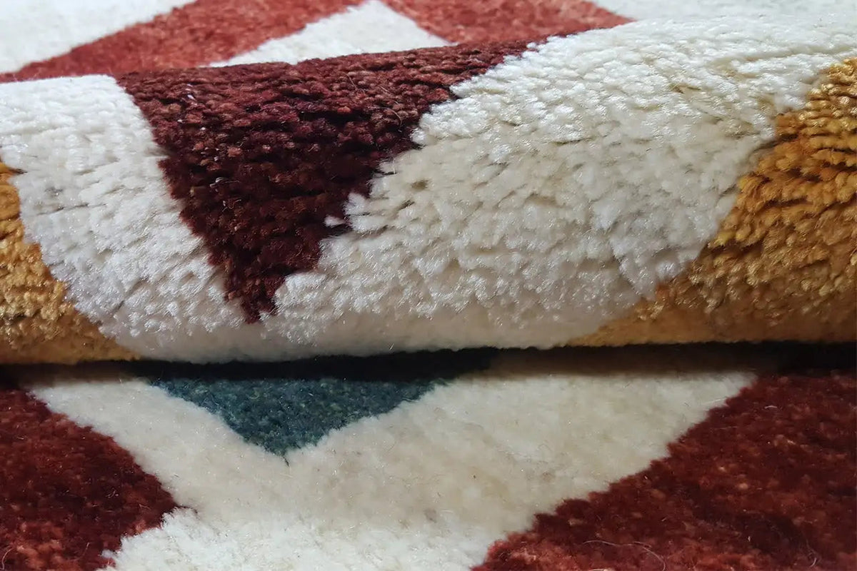 Gabbeh rug detail: pile with contrasting color blocks in red, brown, and cream
