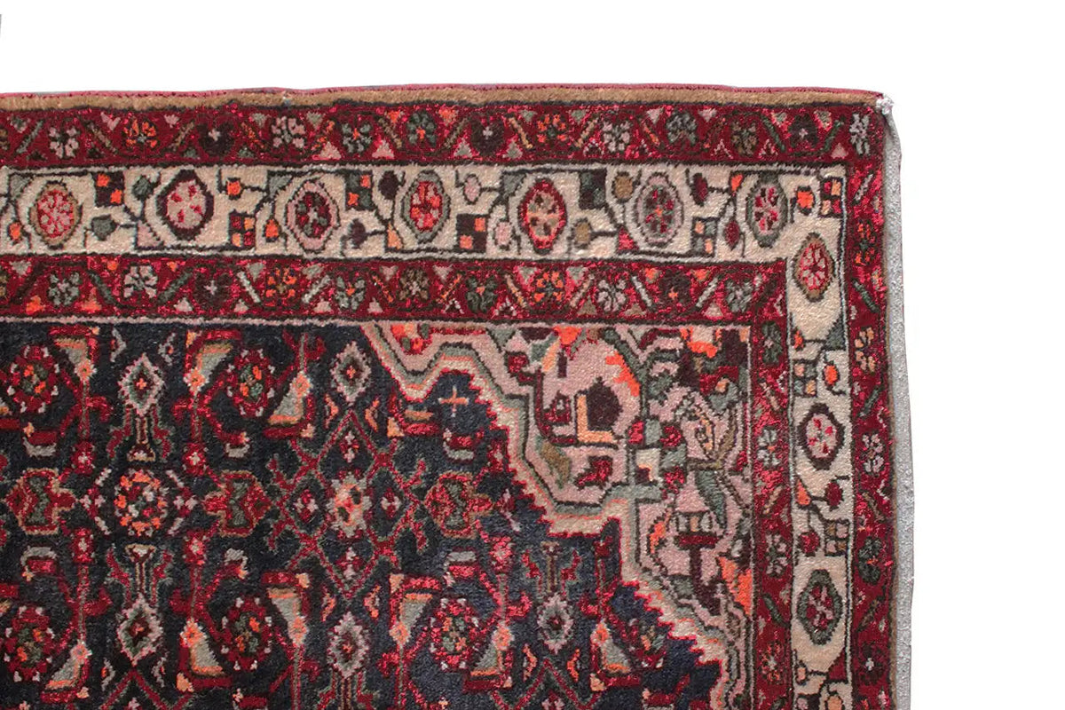 Oriental rug runner with a geometric pattern, dark blue, red, and beige accents, right edge.