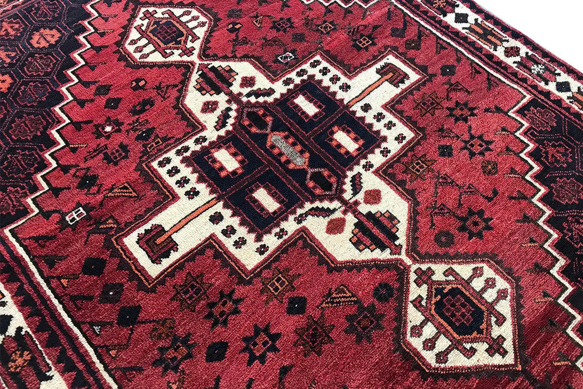 Rug with a red background, white medallions, and dark diamond ornamentation