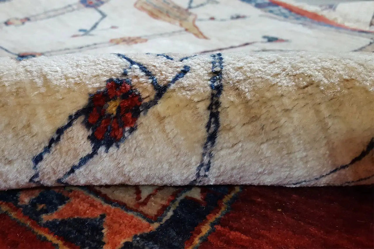 Rug detail: beige pile with a blue ornament and red floral shape