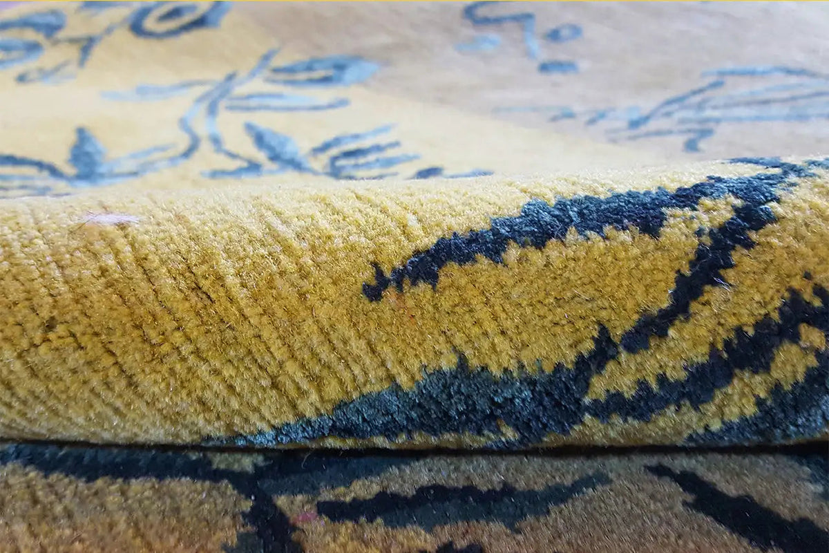 Close-up of a designer carpet: yellow pile with a blue decorative stripe and border detail