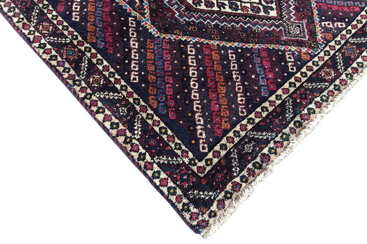 Corner detail of a runner with a zigzag border and ornamental diamonds, colorful