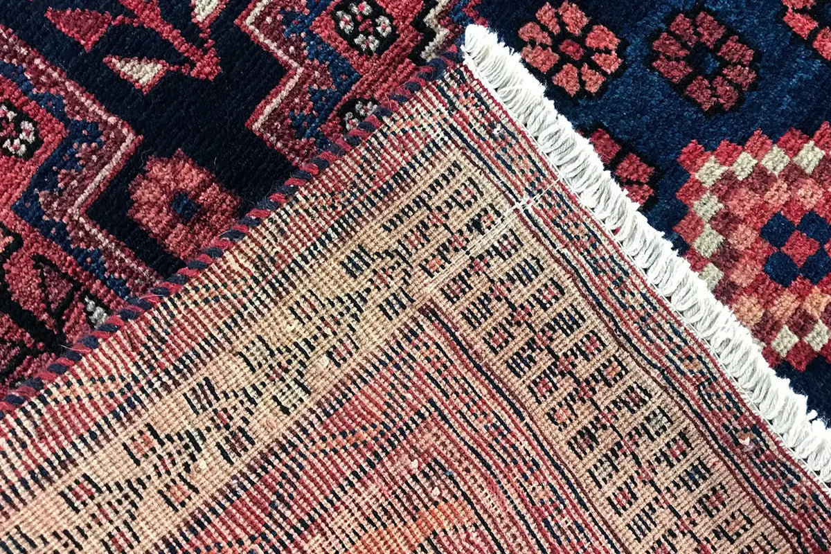 Carpet detail with a dense weave, red-and-white patterns, and a bound edge