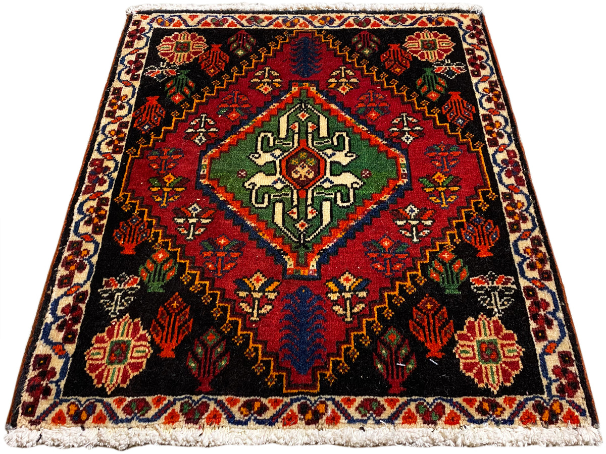 Square Poshti rug, black background with a central pattern in green, red, and blue