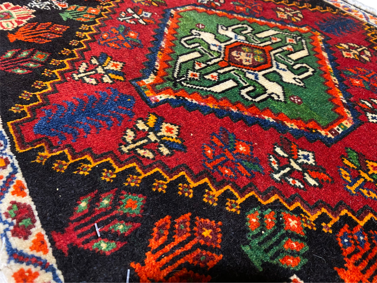 Poshti rug close-up of a corner: multicolored geometric ornaments on a black background