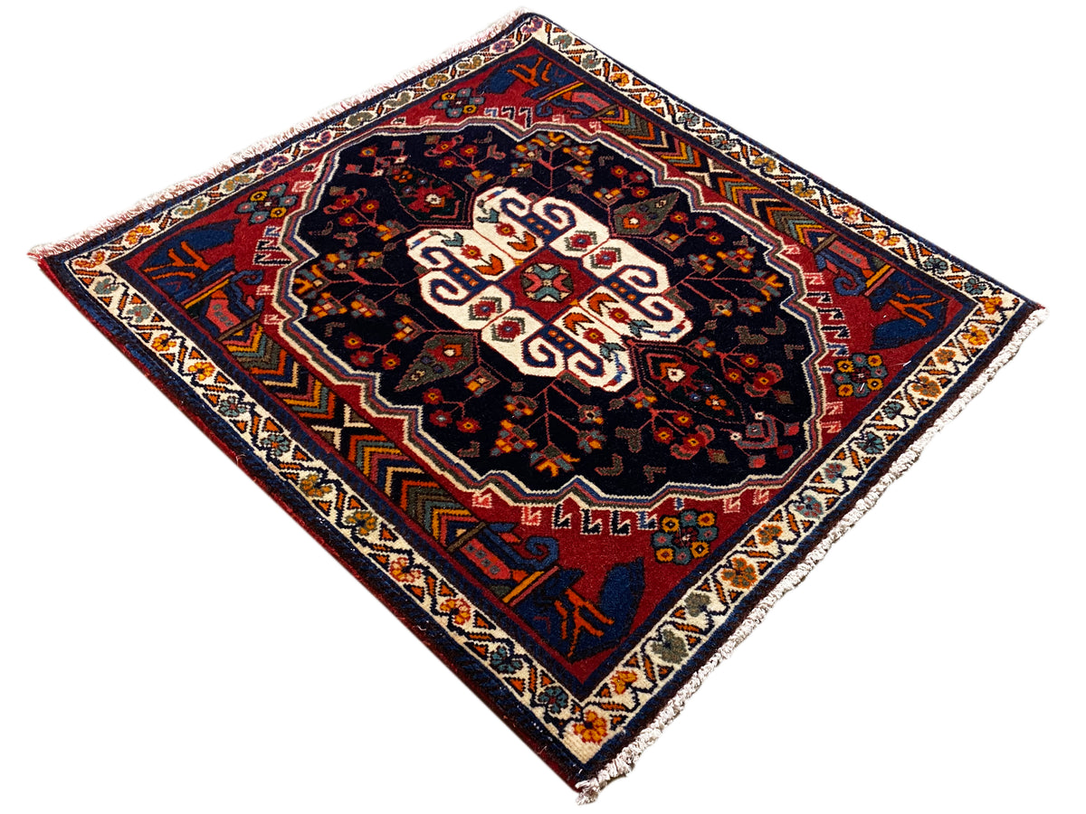 Poshti rug in a diamond pattern with a dark background and white central ornament