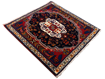 Poshti rug in a diamond pattern with a dark background and white central ornament