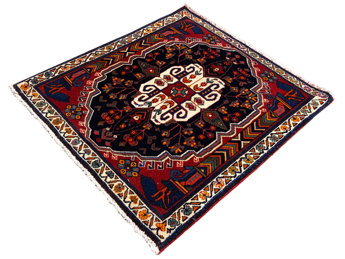 Poshti square rug with a dark pattern, red accents, and a white medallion