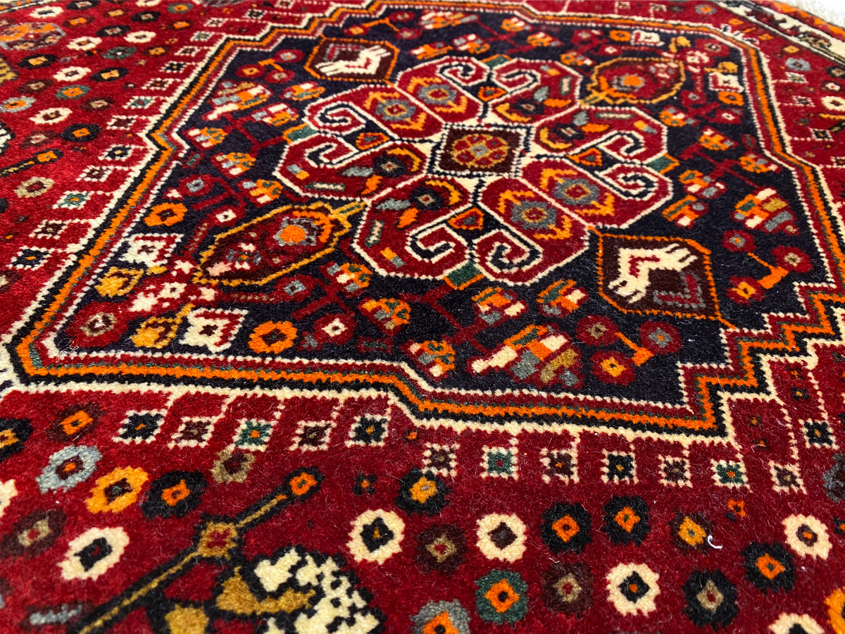 Poshti rug 60x60 cm, close-up of the colorful central ornament on a red background