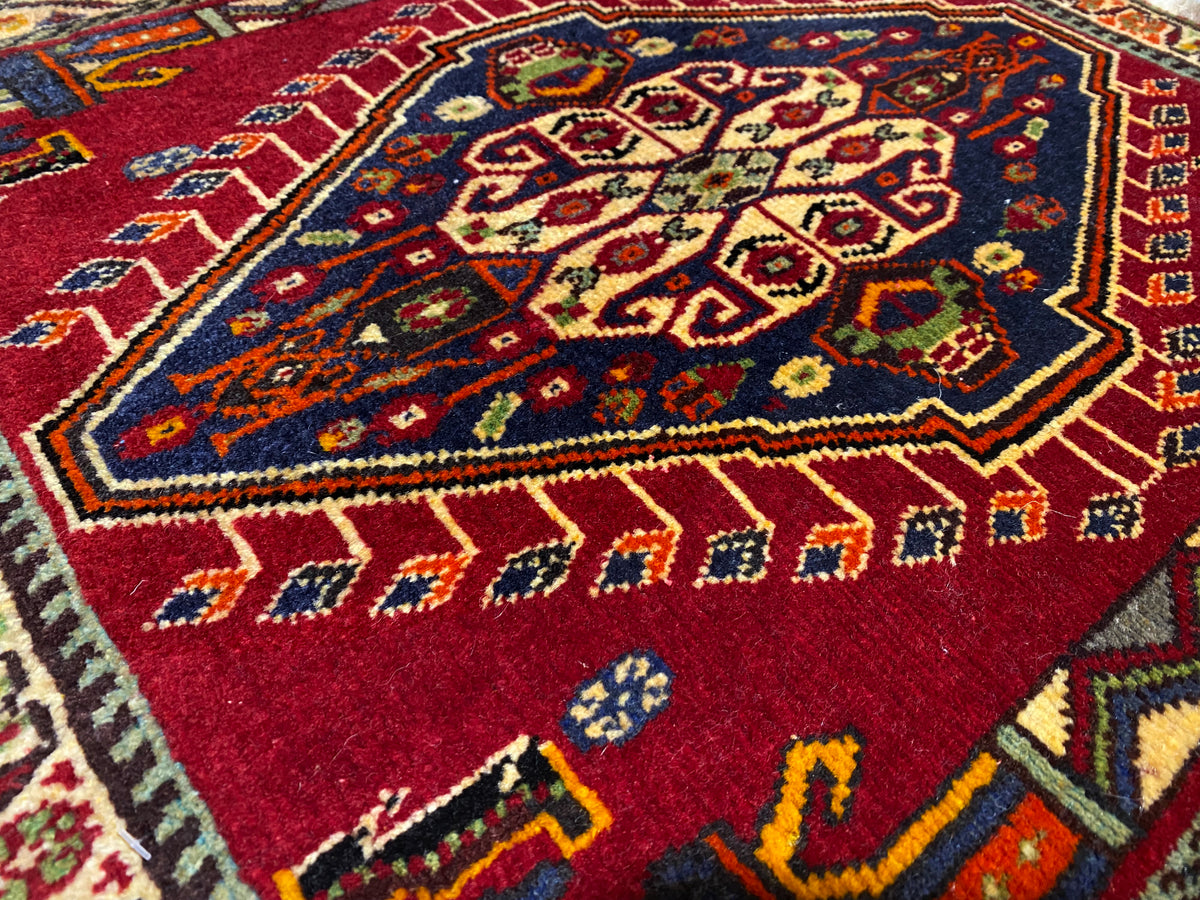 Close-up of Poshti rug (59×61 cm): red inner pattern with colorful ornaments and border