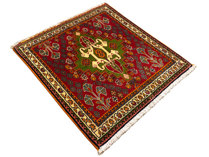 Red oriental rug with cross and vine motifs, green accents, and a decorative border