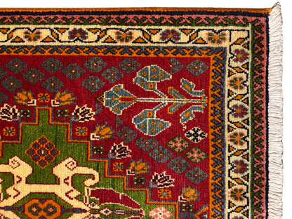 Close-up: oriental rug with a red background, green squares, a patterned border, and fringes