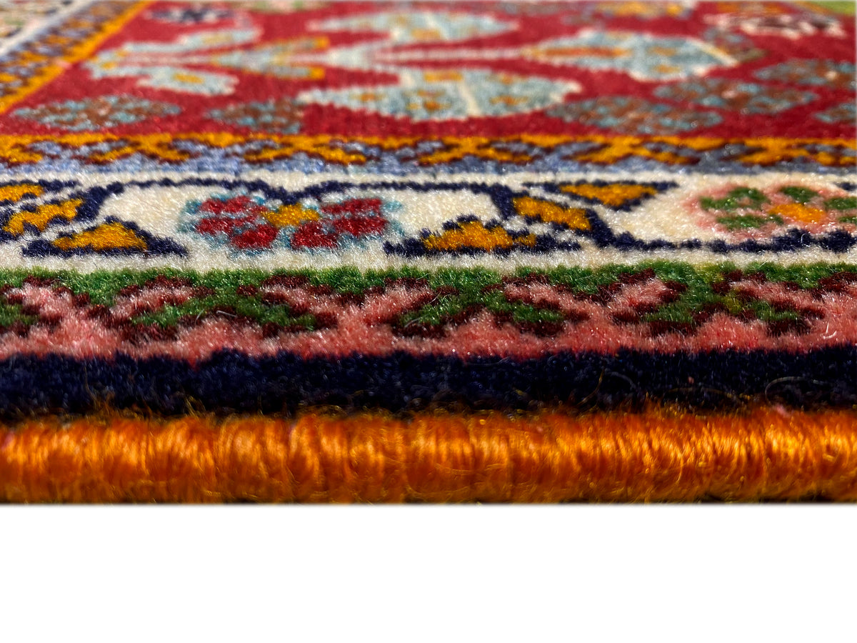 Carpet edge in detail: dense pile with a red background and colorful ornaments