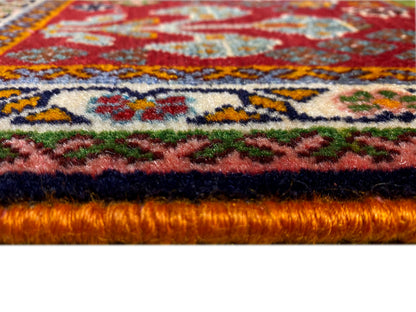 Carpet edge in detail: dense pile with a red background and colorful ornaments