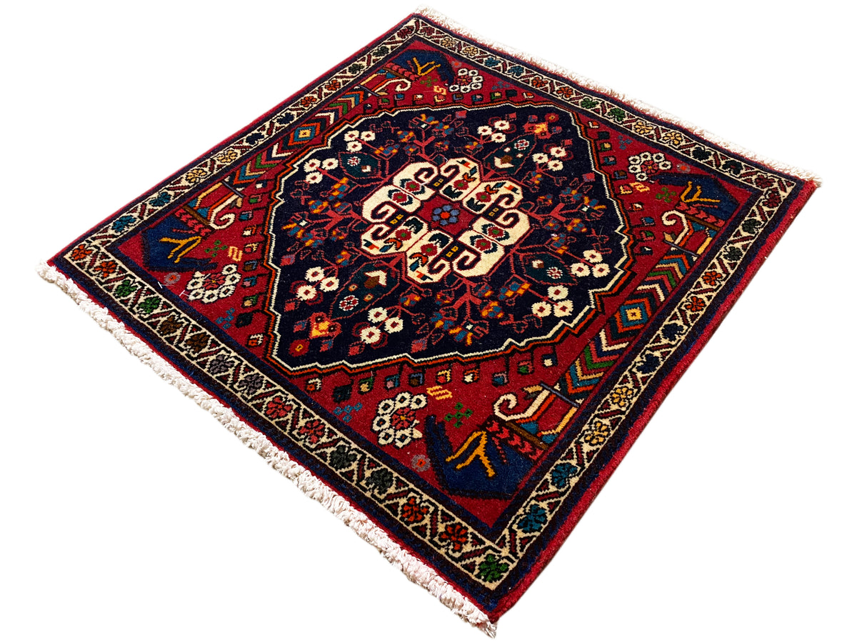 Square rug with a decorative border, a red-and-blue pattern, and a cream-colored central field