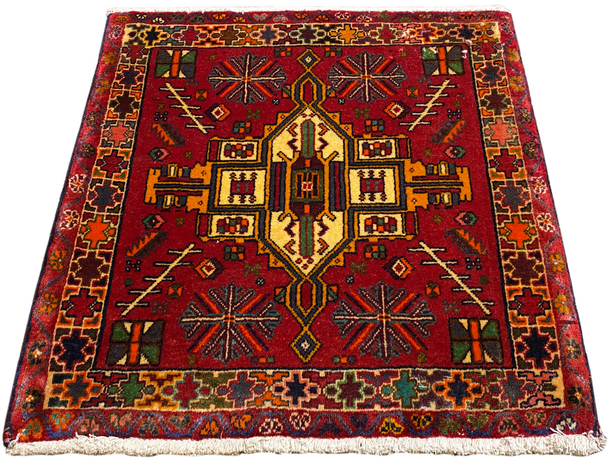 Poshti rug in red with a symmetrical central pattern and multicolored border
