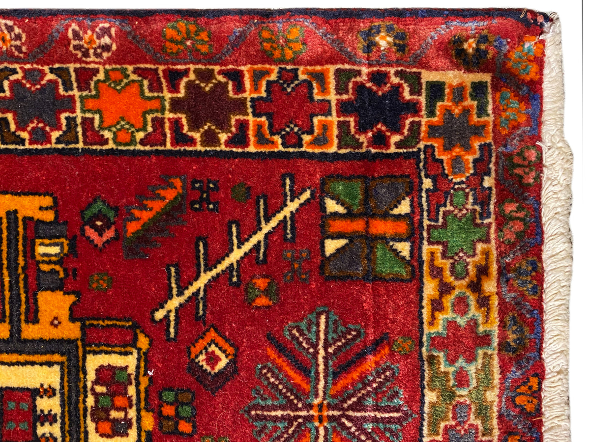 Close-up: Poshti rug with a red background, colorful ornaments, and a multicolored border
