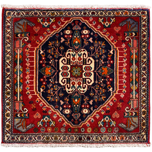 Square rug with a red background and dark blue central motif, with fringes