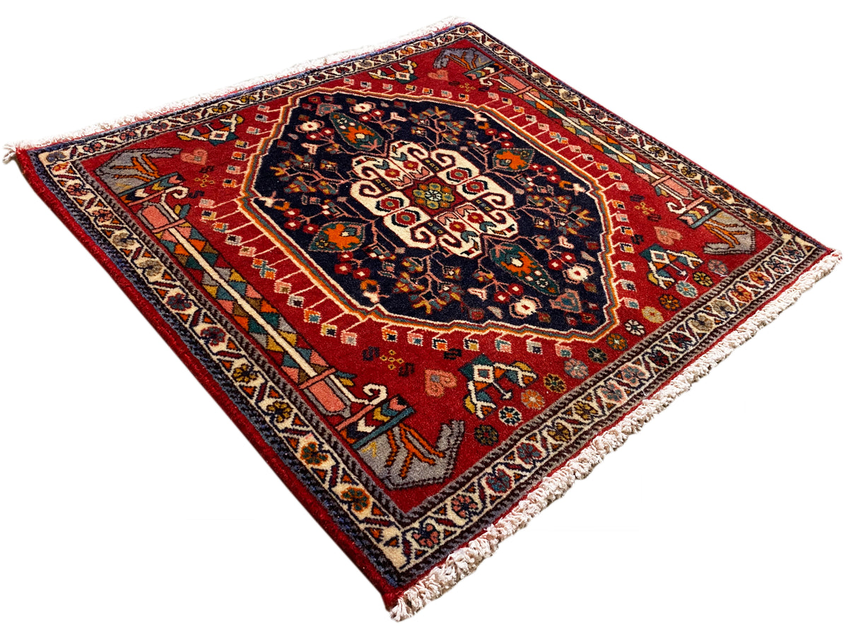Rectangular rug with a red background and blue ornamental pattern, with fringes