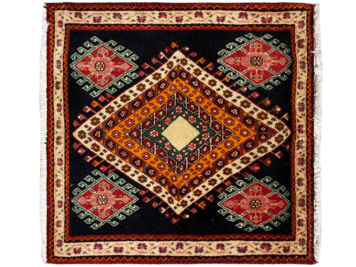 Poshti rug with a black background, an orange-yellow diamond, and four green and red medallions